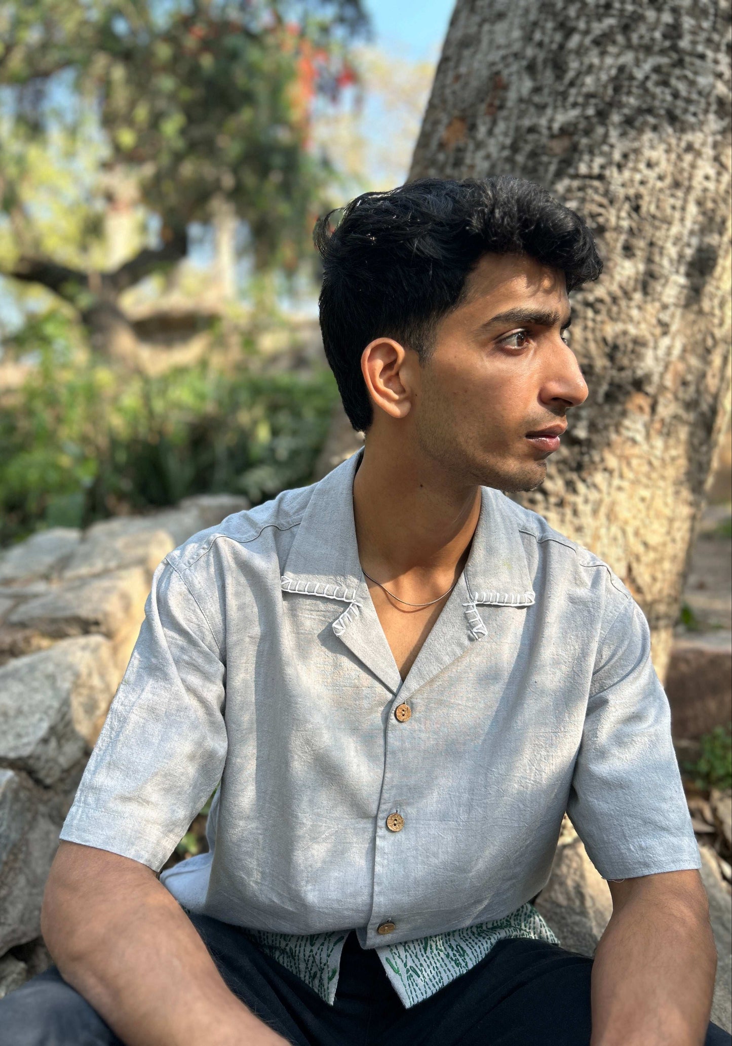 Pearl grey handloom cotton shirt for men with floral meadow embroidery on the hem, seated view