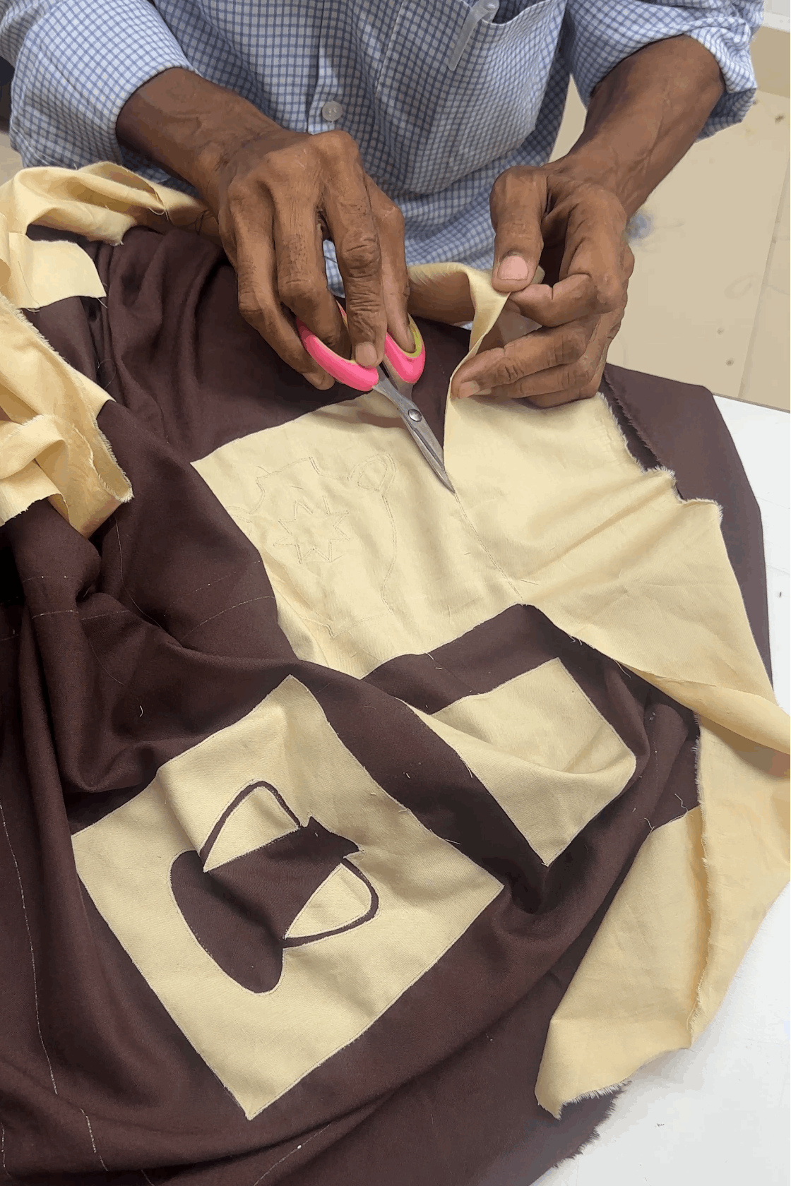 Artisan hand embroidering the pottery appliqué, the making of the Ajanta Applique Shirt by Oje'