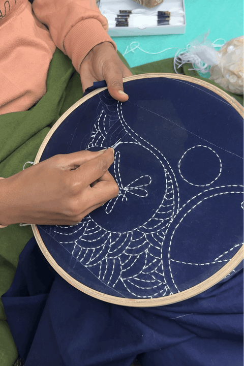 Artisan hand embroidering kantha circle motifs, the making of the Ziro Embroidered Shirt by Oje'