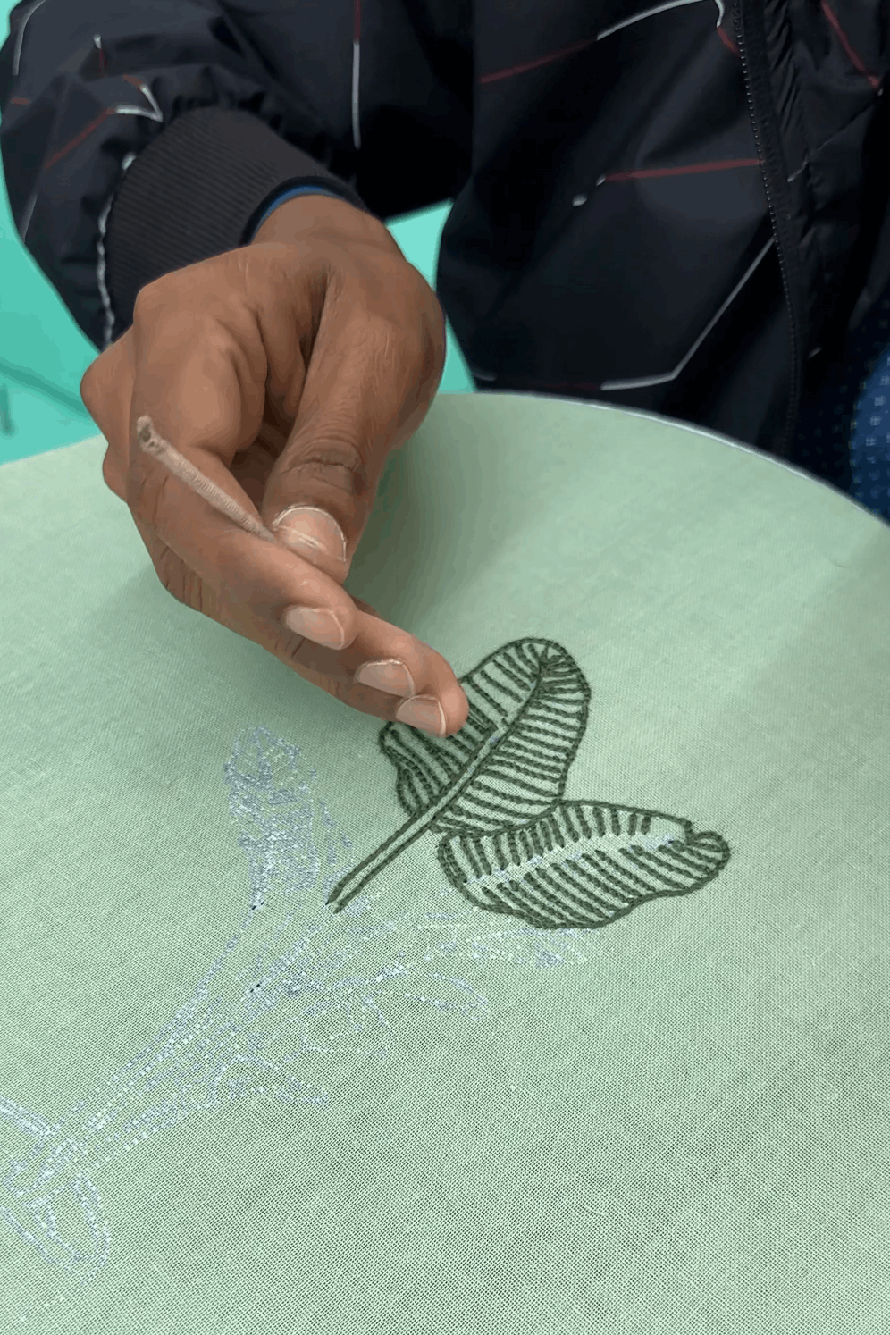 Artisan hand embroidering a banana leaf motif, the making of the Munnar Embroidered Shirt by Oje'
