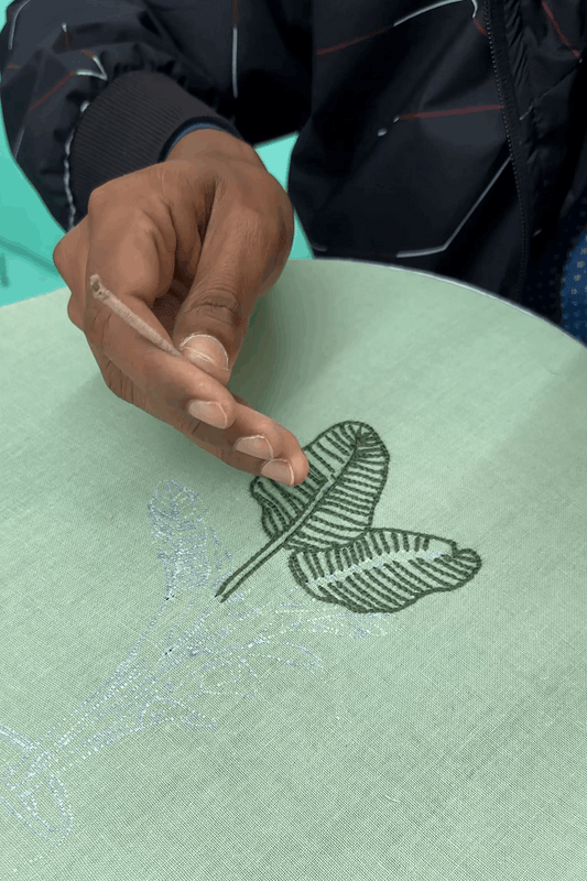 Artisan hand embroidering a banana leaf motif, the making of the Munnar Embroidered Shirt by Oje'
