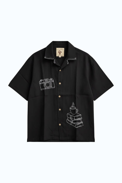 Black modal shirt with hand embroidered camera and coffee motifs, flat lay