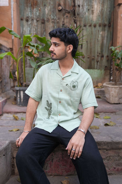 Sage green double cloth cotton shirt for men with aari hand embroidered garden motifs, seated view