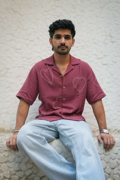 Mauve pink double cloth cotton shirt for men with kantha hand embroidered heart motifs, seated three-quarter view