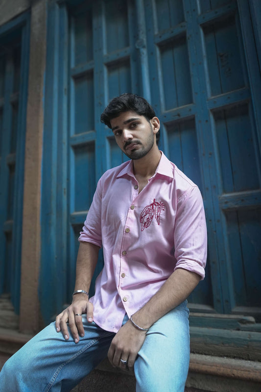 Blush pink cotton satin shirt for men with hand embroidered chilli motif, seated three-quarter view