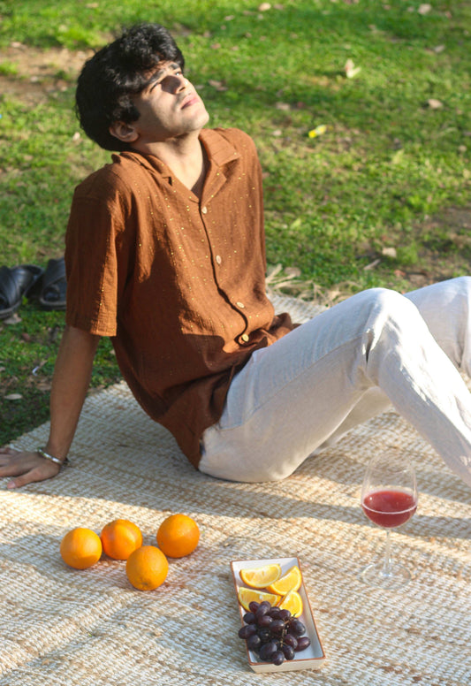 Caramel brown textured cotton shirt for men with golden woven stripes, seated picnic view